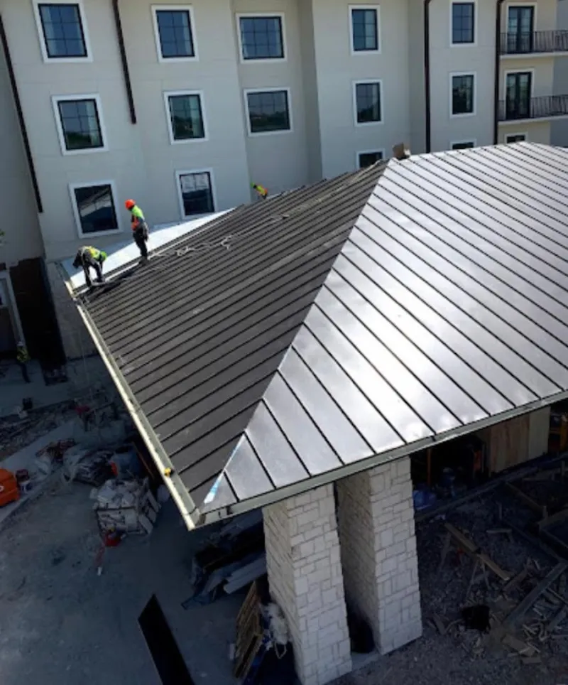 Crew installing standing seam metal roof panels on a commercial project in East Hampton